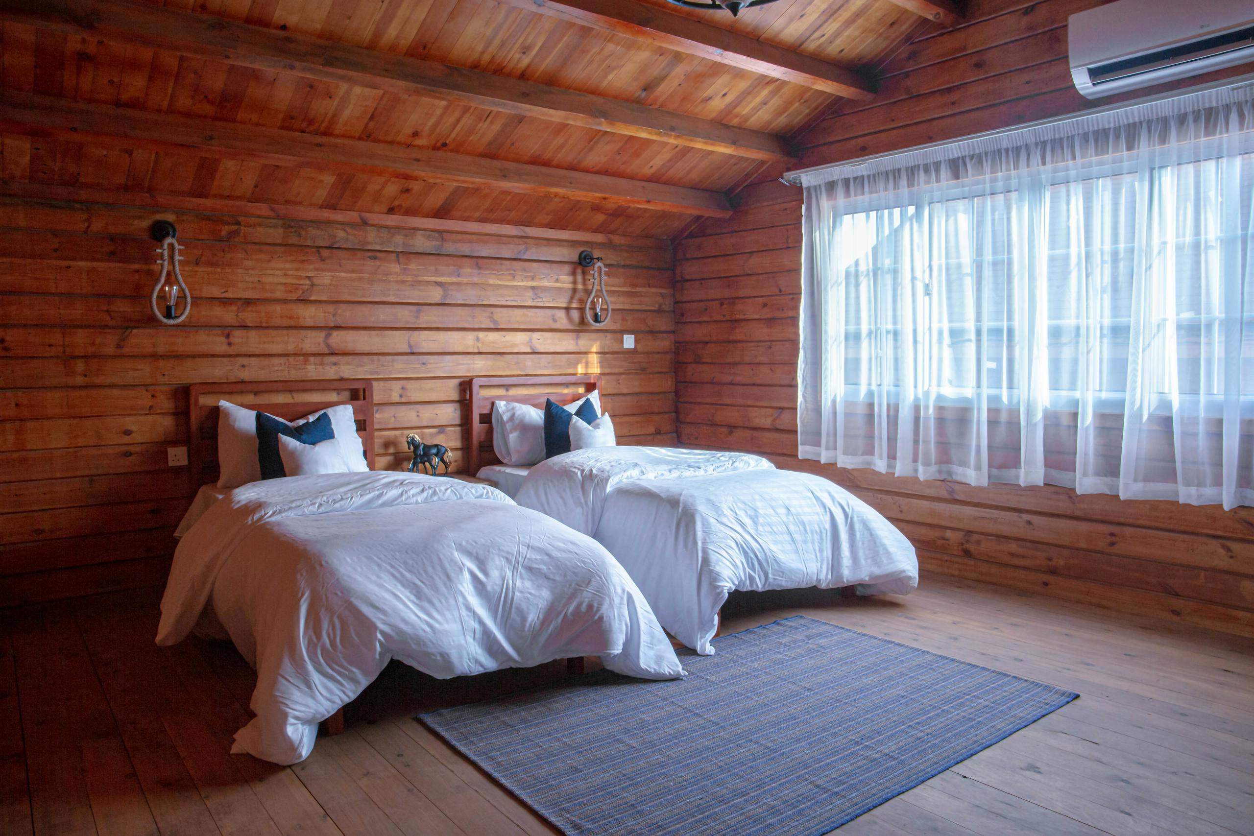 Comfortable log cabin bedroom featuring twin beds, natural wood design and soft lighting.